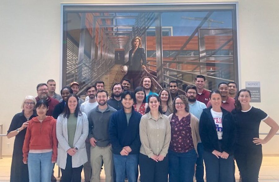 A group of people standing in front of a large picture